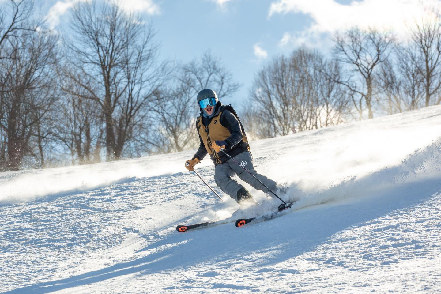 Skier descending a snowy slope on a sunny day.