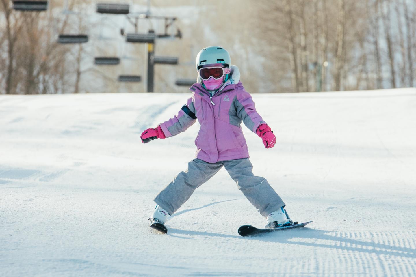 Child skiing downhill, wearing a pink jacket and helmet.