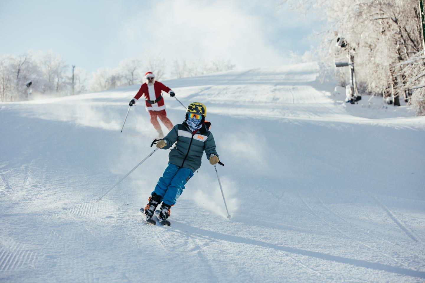 Two skiers descending a snowy slope on a sunny day.