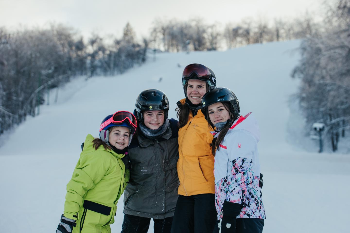 Family wearing ski gear standing on a snowy slope.