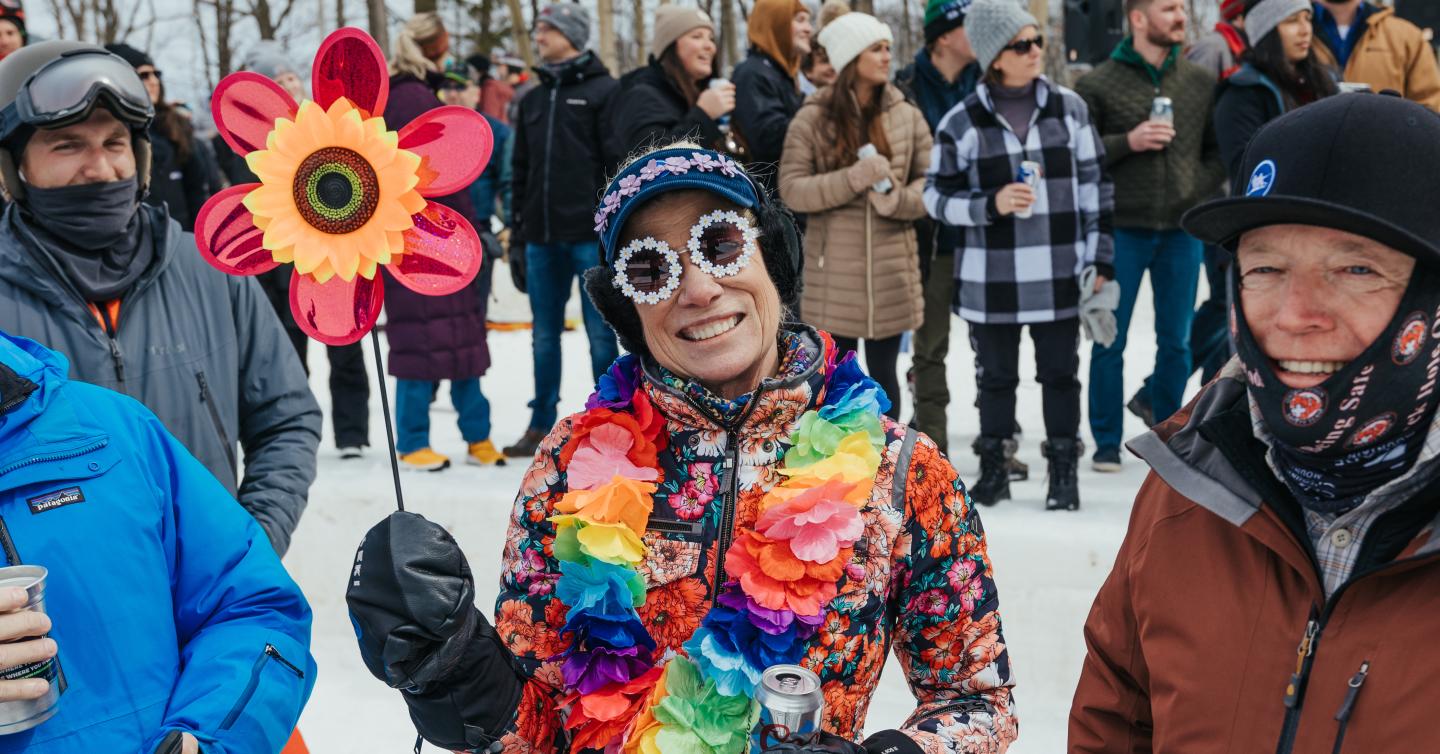 Smiling person in colorful flower costume at a winter crowd gathering.