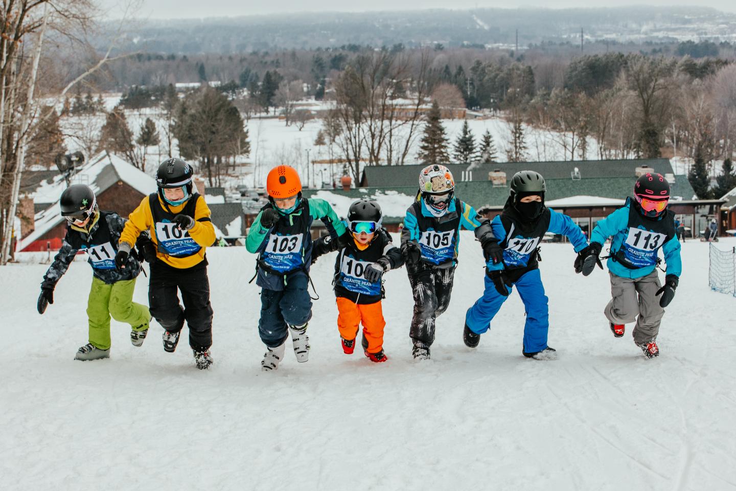 Five snowboarders in colorful gear riding downhill together.